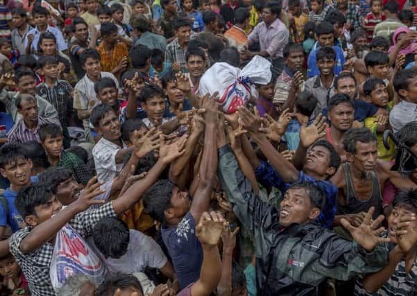Rohingya Muslims, who crossed over from Myanmar into Bangladesh, stretch their arms out to collect food items distributed by aid agencies. (AP Photo/Dar Yasin)