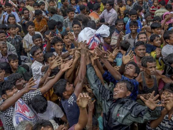 Rohingya Muslims, who crossed over from Myanmar into Bangladesh, stretch their arms out to collect food items distributed by aid agencies near Balukhali refugee camp,