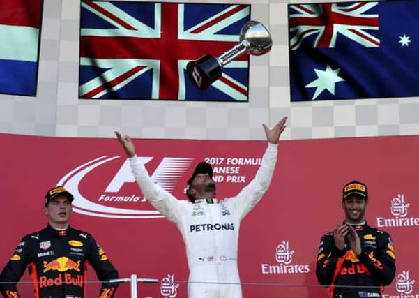 Mercedes' Lewis Hamilton throws his trophy as he celebrates winning the Japanese Grand Prix at Suzuka. Picture: AP/Toru Takahashi.