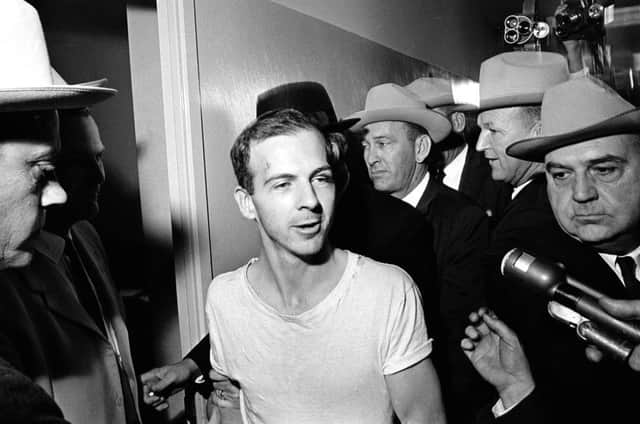 Surrounded by detectives, Lee Harvey Oswald talks to the media as he is led down a corridor of the Dallas police station