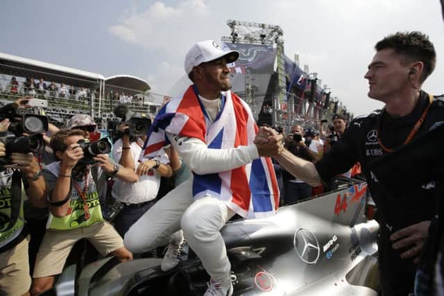 British driver Lewis Hamilton celebrates winning his fourth Formula One championship with a member of his team.