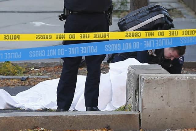 A paramedic looks at a body covered under a white sheet along the bike path. (AP Photo/Bebeto Matthews)