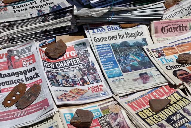 Newspapers are held down by rocks to stop them blowing away at a news stand in Harare, Zimbabwe Monday, Nov. 20, 2017. Longtime President Robert Mugabe ignored a midday deadline set by the ruling party to step down or face impeachment proceedings, while Zimbabweans stunned by his lack of resignation during a national address vowed more protests to make him leave. (AP Photo/Ben Curtis)