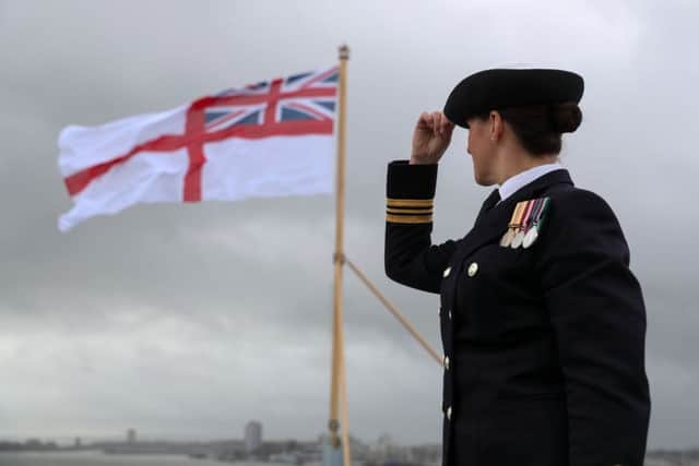 Lt Commander Lindsey Waudby looks up at the White Ensign as it flies at the stern of HMS Queen Elizabeth after her commissioning ceremony in Portsmouth.