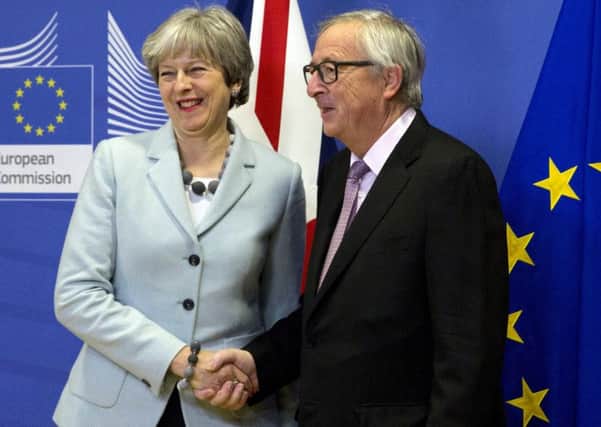 Theresa May and Jean-Claude Juncker shake hands on their Brexit deal.