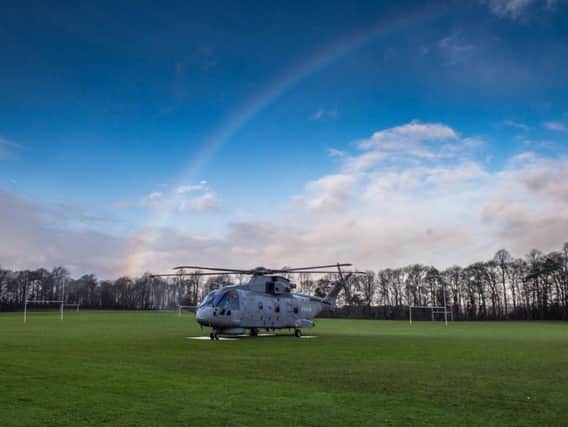 A rainbow can be seen in the background as the helicopter lands on the rugby pitch