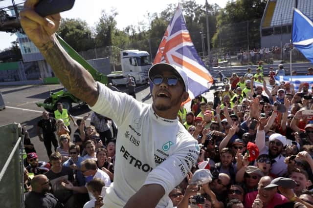 Mercedes driver Lewis Hamilton of Britain takes a selfie with supporters after winning the Italian Formula One Grand Prix, in September