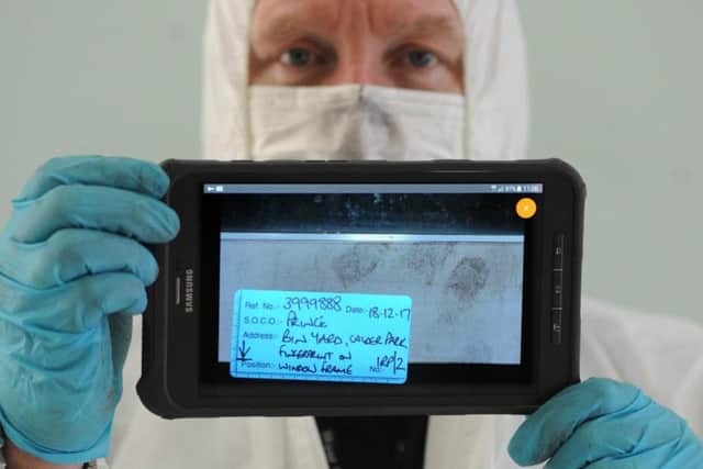 Senior crime scene investigator Ian Prince transfer the picture to his tablet, ready to transmit it digitally from the scene back to the identification bureau.