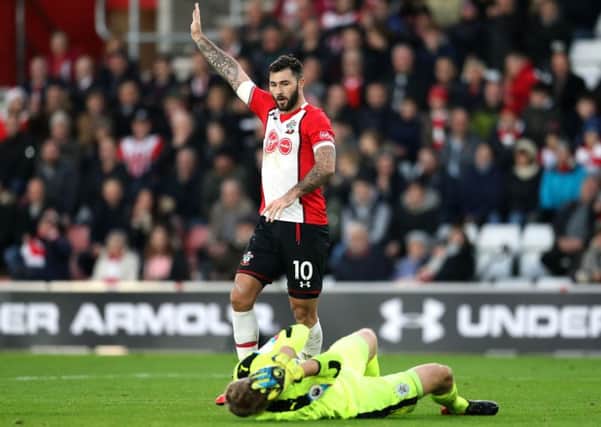 Southampton's Charlie Austin signals whilst Huddersfield Town goalkeeper Jonas Lossl lies injured on the pitch.