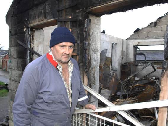 Andrew Warren next to his parent's fire damaged home