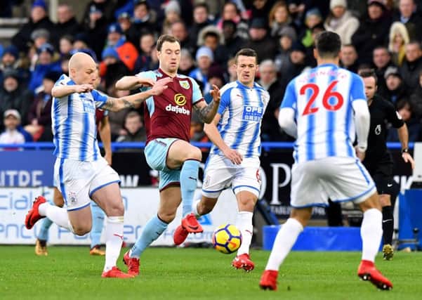 Burnley's Ashley Barnes (centre) battles for the ball with Huddersfield Town's Aaron Mooy at the John Smith's Stadium. Picture: Anthony Devlin/PA