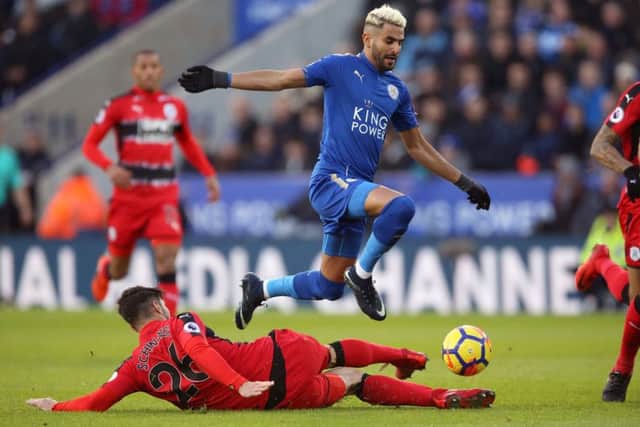 Leicester City's Riyad Mahrez (right) and Huddersfield Town's Christopher Schindler battle for the ball at the King Power Stadium. Picture: Nigel French/PA.