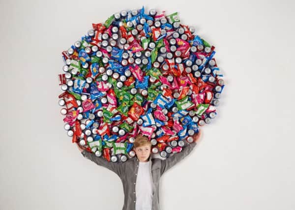 Harry Way surrounded by 500 packets of crisps, biscuits and fizzy drinks, as a report says that teenagers who watch lots of TV with adverts are more likely to eat junk food, suggesting a "strong association between advertisements and eating habits."