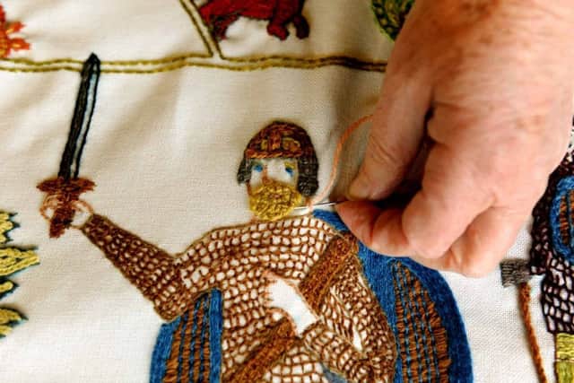 An embroiderer working on the figure of King Harold  in the Battle of Fulford tapestry at the Merchant Adventurers Hall in York.