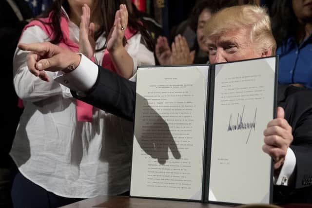President Donald Trump holds up an Executive Order on "Improving Accountability and Whistleblower Protection" after signing it at the Department of Veterans Affairs, Thursday, April 27, 2017, in Washington. (AP Photo/Andrew Harnik, File)