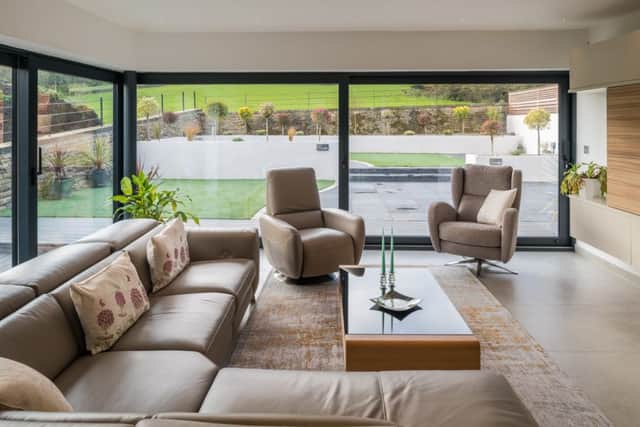 The sitting area in the open-plan living space with views over garden. On the right is a bespoke shelving/media unit