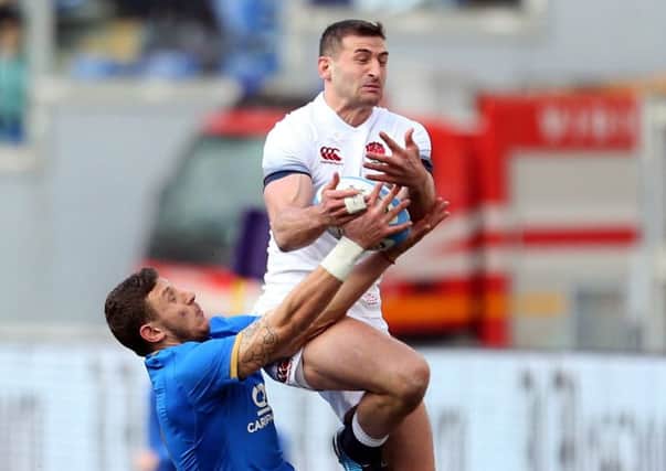 England's Jonny May catches the ball under pressure from Italy's Matteo Minozzi.