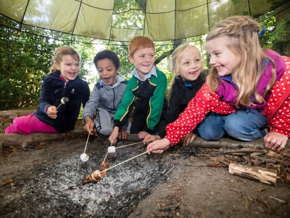Pupils at Belmont Grosvenor toasting marshmallows around the campfire during a Forest School session in the grounds of the school.