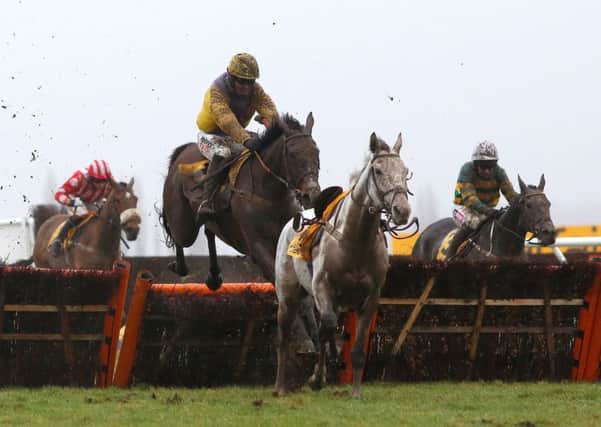 Jack Quinlan and Kalashnikov (yellow cap) avoid a loose horse at the final flight before going on to win The Betfair Handicap Hurdle Race at Newbury.