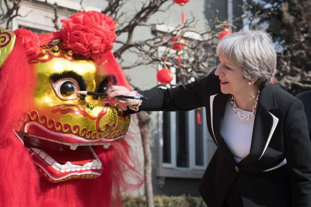 Prime Minister Theresa May 'dots the eye' of a Chinese dragon, a traditional ritual of awakening a dragon Photo : Stefan Rousseau/PA Wire