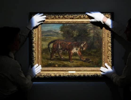 Gallery assistants straighten Tigre jouant avec une tortue by Eugene Delacroix during a photo call for highlights from the collection of Peggy and David Rockefeller at Christie's in London.
