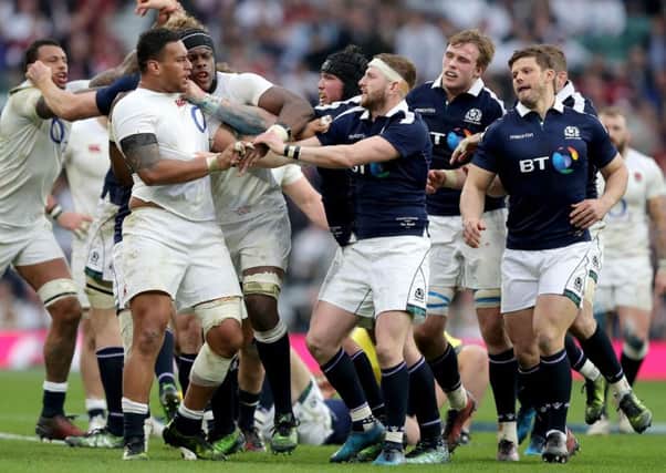 England's Nathan Hughes (left) and Scotland's Finn Russell (centre) tussle along with team-mates at Twickenham in March last year. Picture: Andrew Matthews/PA