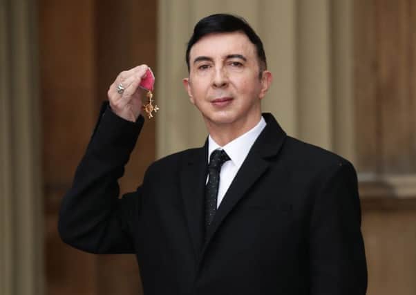 Soft Cell frontman Marc Almond holds his OBE following an investiture ceremony at Buckingham Palace