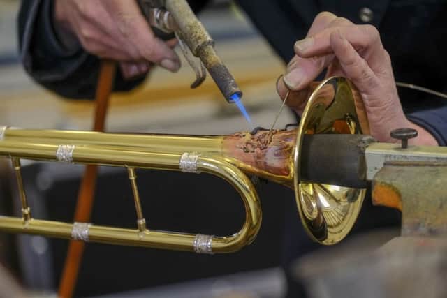 Richard Wright in the workshop of Smith Watkins attaching the Royal Coat of Arms to one of the new set of ceremonial fanfare trumpets.
