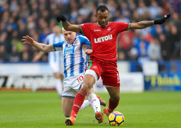 Huddersfield Town's Aaron Mooy (left) and Swansea City's Jordan Ayew battle for the ball.