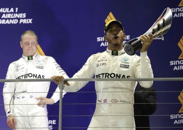 Valtteri Bottas looks on as Mercedes team-mate Lewis Hamilton, right, of Britain celebrates on the podium after winning the Singapore Formula One Grand Prix in 2017