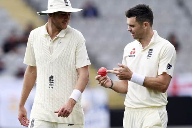 England's Stuart Broad, left and James Anderson discuss the pink ball against New Zealand during the first cricket cricket test in Auckland, New Zealand (AP Photo/Ross Setford)
