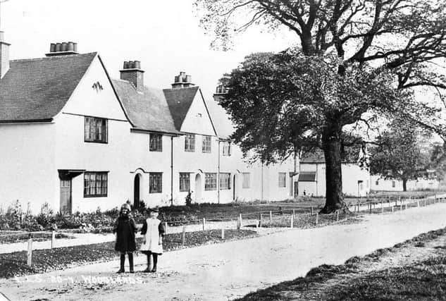 Two girls pose for a photograph outside Woodlands cottages.