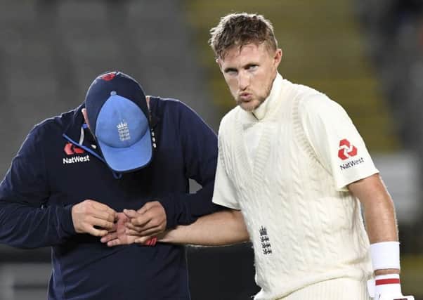 England's Joe Root, right, receives attention for an injured finger after being hit by a ball from New Zealand's Trent Boult Picture: AP/Ross Setford