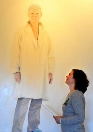 Katt Nellist from Beningbrough Hall looks at a giant painting of Dame Judi Dench by  Alessandro Raho