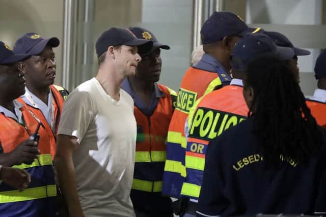 Australian cricket player Steve Smith, escorted by police officers to a departure area at OR Tambo International airport in Johannesburg. (AP Photo/Themba Hadebe)