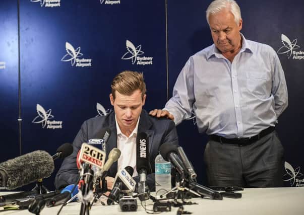 Former Australian captain Steve Smith is comforted by his father Peter at a news conference.
