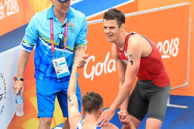 Helping hand: Scotland's Marc Austin is helped up by England's Jonathan Brownlee after winning bronze.
