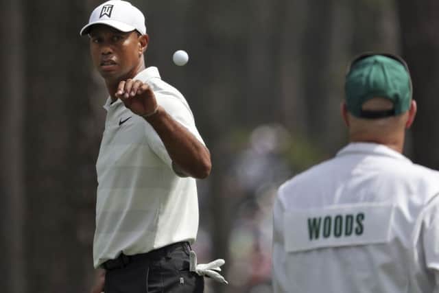 Tiger Woods, left, catches a ball tossed by his caddie Joe LaCava as he gets ready to putt during the second round of the Masters at Augusta. Picture: Jason Getz/AP