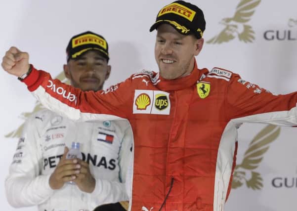 Ferrari driver Sebastian Vettel of Germany celebrates on the podium after winning the Bahrain Formula One Grand Prix, flanked by third place Mercedes driver Lewis Hamilton. (AP Photo/Luca Bruno)