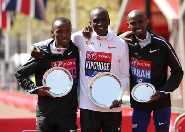 Kenya's Eliud Kipchoge (centre) poses with the trophy after winning the Men's London Marathon alongside second placed Ethopia's Tola Shura Kitata (left) and third placed Great Britain's Sir Mo Farah.