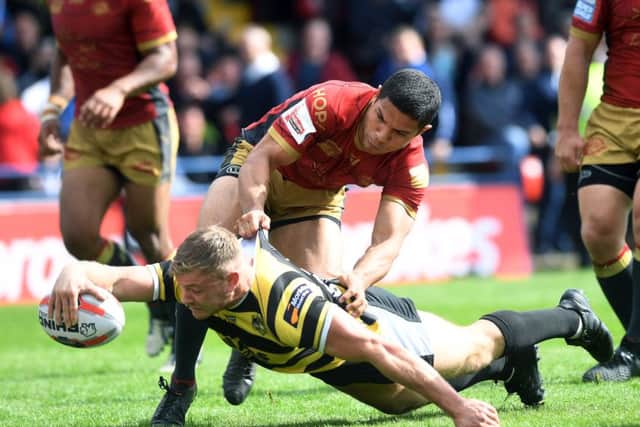 York's Joe Porter scores his first try despite the effots of Catalans David Mead. Picture Jonathan Gawthorpe
