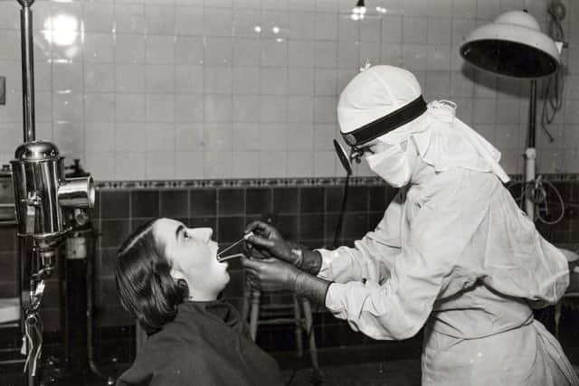 A nurse in a white gown and cap taking a throat swab from a patient, at Middlesex Hospital