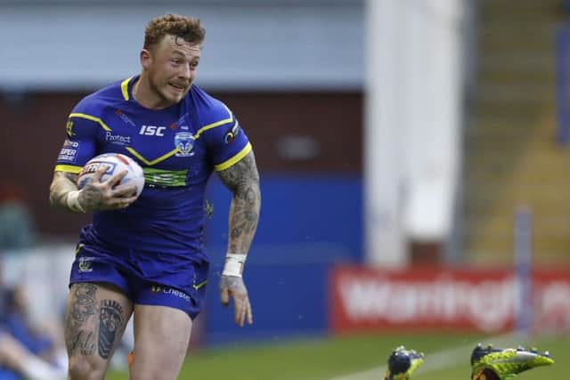 Warrington Wolves' Josh Charnley skips away from Huddersfield Giants Jared Simpson to score a try.