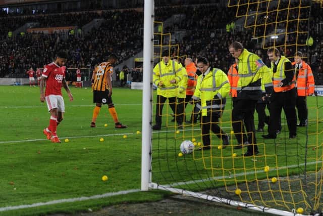 Stewards and players clear the pitch of yellow balls thrown during Hull City's fans' 19th-minute protest during the game against Nottingham Forest in October last year.  Picture: Bruce Rollinson