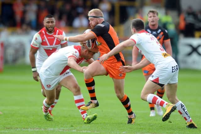 Tigers' Oliver Holmes charges Saints Jon Wilkin and Ryan Morgan.