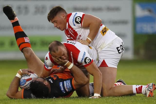 Castleford Tigers' Matt Cook is tackled by St Helens' James Roby and Morgan Knowles.